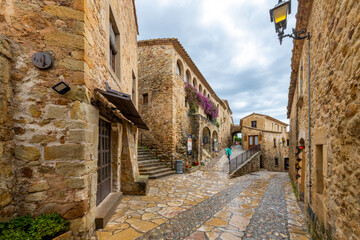 A lone tourist walks the wet streets of the medieval village of Pals Spain after a summer...