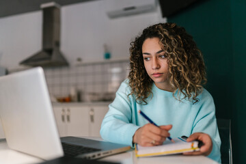 Female student doing homework in kitchen