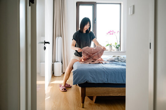 Young Woman Folding Her Laundry At Home