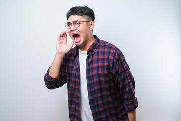 Young asian man shouting and screaming loud to side with hand on mouth