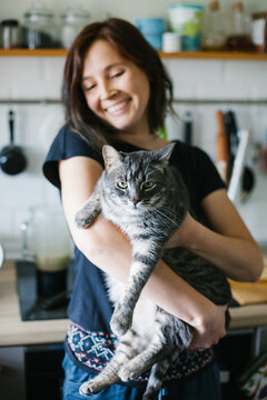 Happy woman with cat in kitchen