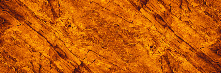 Orange red brown rock texture with cracks. Rough mountain surface. Close-up. Stone background for design. Crushed, broken, crumbled. Web banner. Wide. Panoramic.	