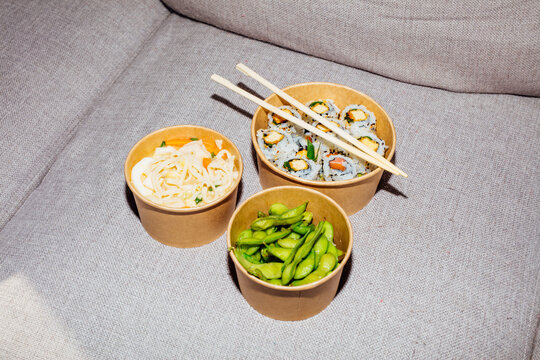 Sushi, ramen, edamame in a takeaway boxes