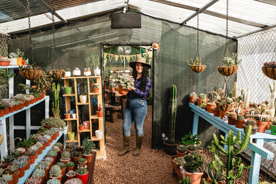 Smiling woman in her store selling plants, cacti and succulents. 