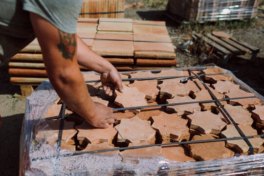 Man placing finished tiles in pallets
