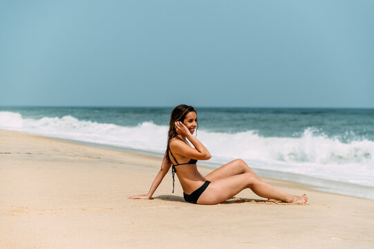 Slim woman in bikini standing on sandy beach
