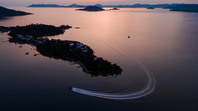 speedboat turning around an island in the sunset