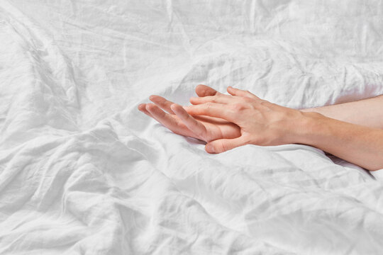 Close up of two loving people holding hands in bed