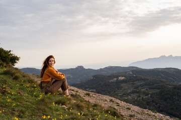 Portrait of happy woman sitting on grass in nature at sunset