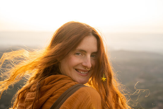 Portrait of happy carefree woman in nature at sunset wearing flowers