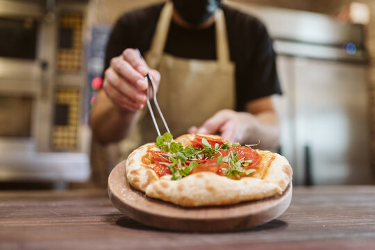Chef garnishing a fresh pizza