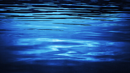 Reflection of light on the surface of the water. Night time. Little waves. Navy blue marine...