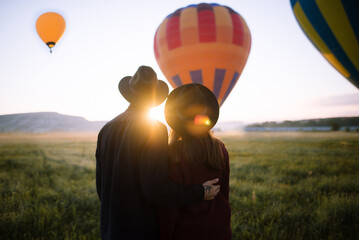 Anonymous couple watching hot air balloons in the air