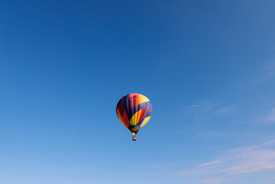 Fototapeta Multicolored hot air balloon in center of blue sky