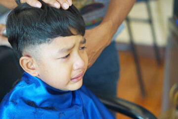 Asian boy, 4 years old, do a hair cuts and cries.       