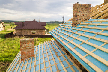 Aerial view of a brick house with wooden roof frame under construction