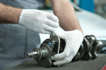 Spare parts for a passenger car. The crankshaft.  An auto mechanic measures the crankshaft crank...