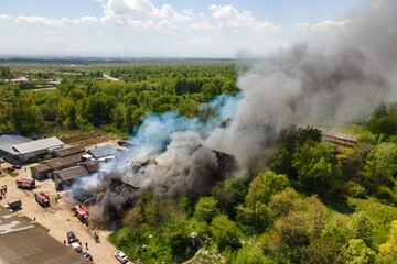 Aerial view of firefighters extinguishing ruined building on fire with collapsed roof and rising...