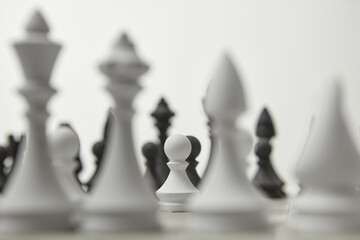 Chess figures with a white pawn in the focus.