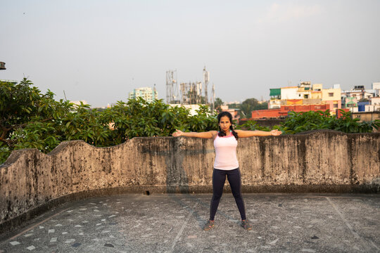 Indian woman doing physical exercise in a rooftop in urban area