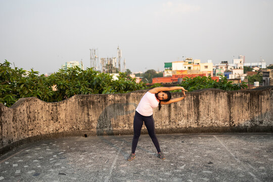 Indian woman doing physical exercise in a rooftop in urban area