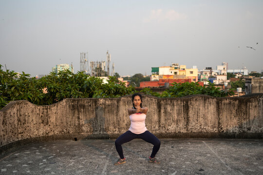 Indian woman doing physical exercise in a rooftop in urban area