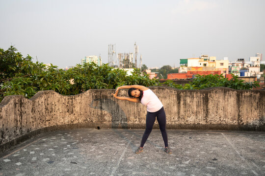 Indian woman doing physical exercise in a rooftop in urban area