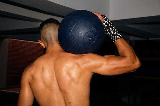 View of the back of a man holding a fitness ball 