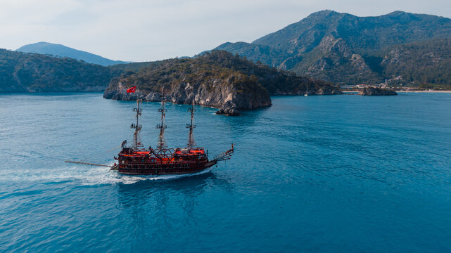 large sailboat styled as a pirate ship passing by islands