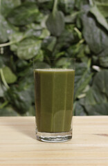 Glass of Fresh Green Juice With Blurred Spinach and Lettuce Leaves in Background