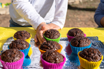 Crop child picking chocolate muffins