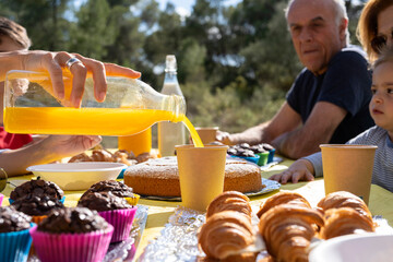 Crop woman pouring juice during child birthday party