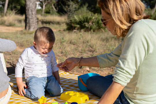 Woman playing with child on picnic blanket
