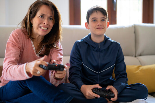 Woman and teen boy playing videogame at home
