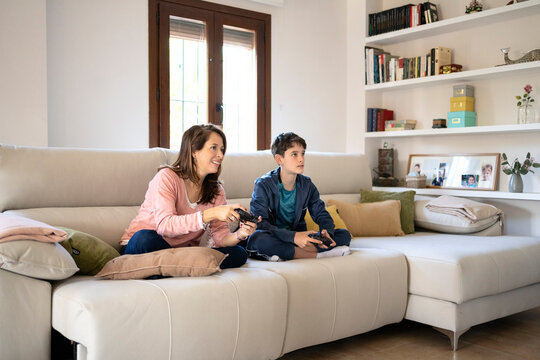 Content mother and son playing videogame on sofa