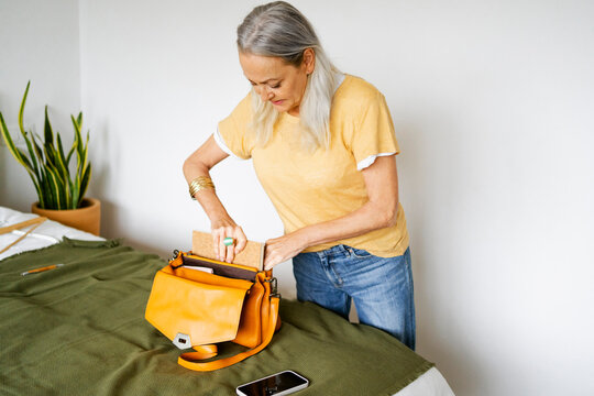Senior woman preparing shoulder bag before leaving