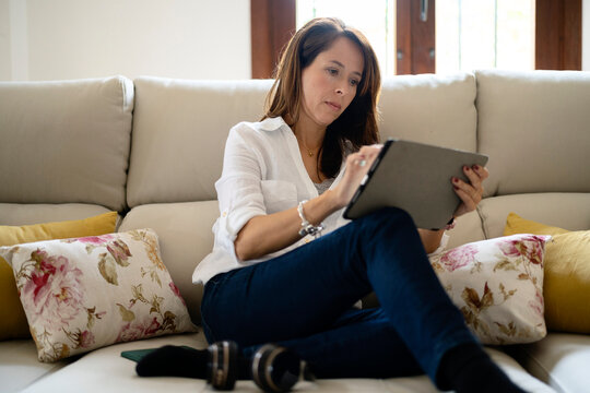 Serious female browsing tablet on settee