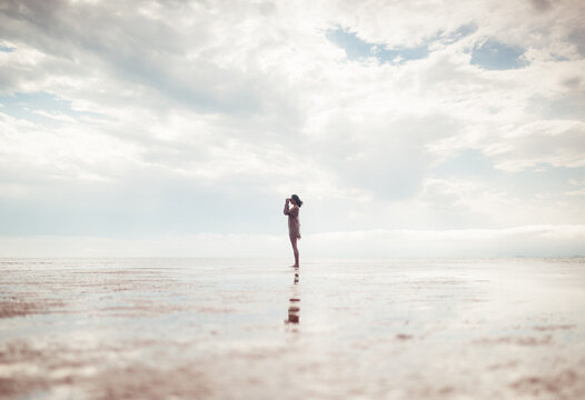 Woman silhouette using binoculars on empty beach