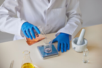 Anonymous pharmacist pouring chemical liquid