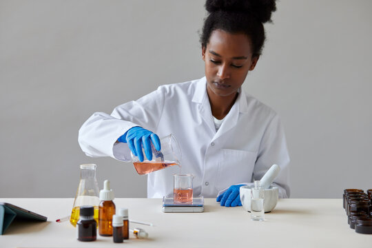 Black pharmacist pouring chemical liquid