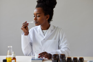 Black pharmacist sniffing skincare product