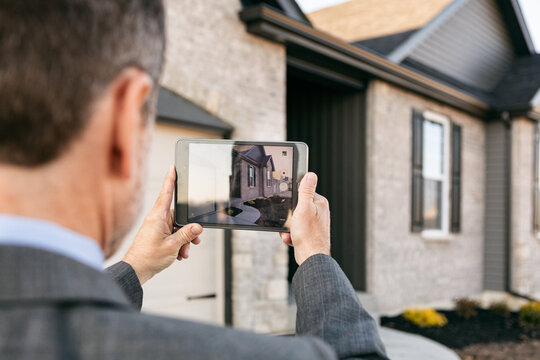 Agent Takes Photo Of Elevation With Tablet