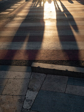 Long shadows of passers-by on the pavement