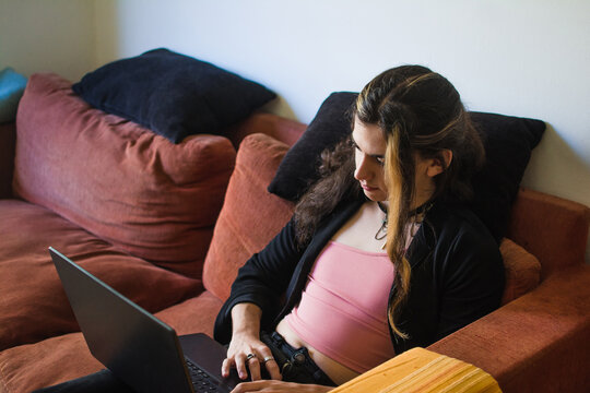 Trans teenage girl using laptop at home
