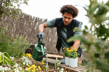 Black male gardener watering plants