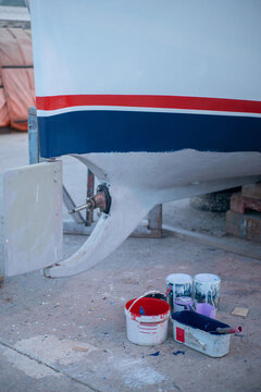 Cans of paint next to an old boat