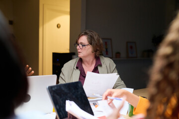Aged businesswoman in glasses with docs at meeting.