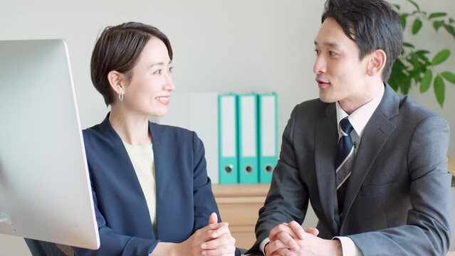 目を合わせて話すスーツを着た日本人男女