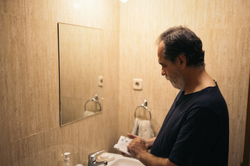 Mature man in the bathroom reading some instructions