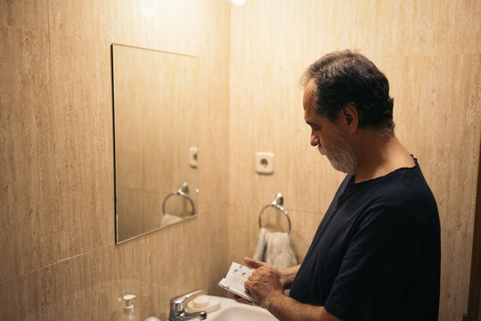 Mature man in the bathroom reading some instructions